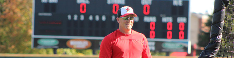 A baseball coach pitches during practice.