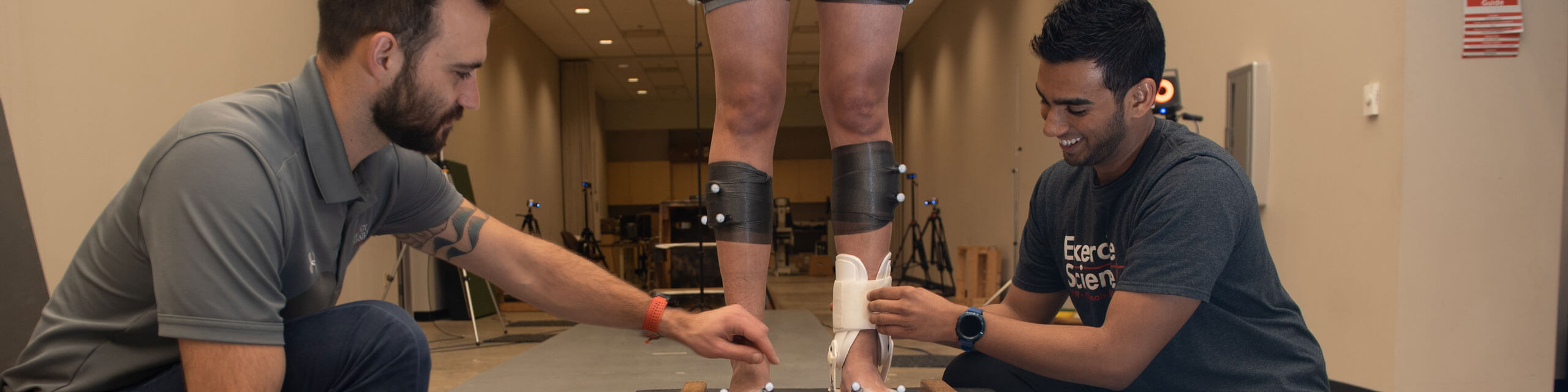 Graduate students use a piece of equipment on a patient's ankle.