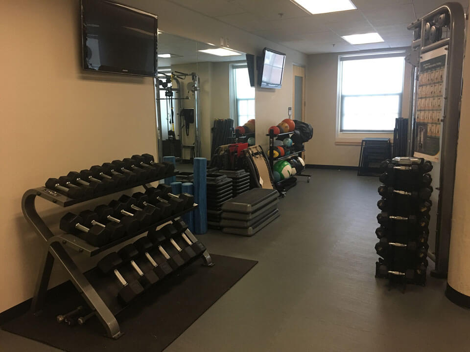 A rack of weights sit against a wall.